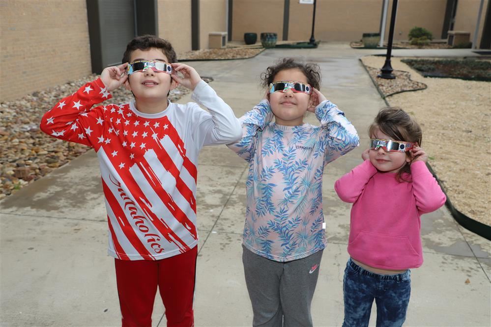  3 students wearing eclipse glasses.